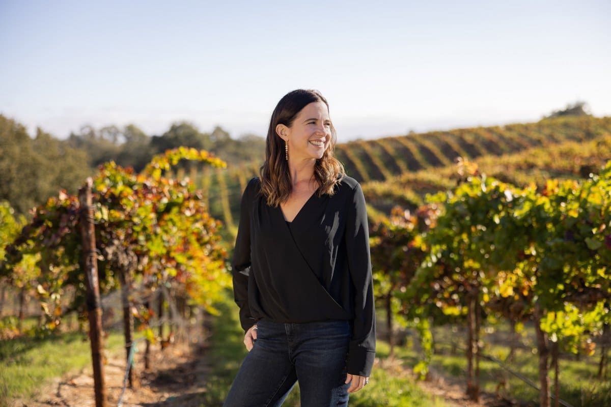 a woman poses in the middle of her California vineyard in this commercial photograph