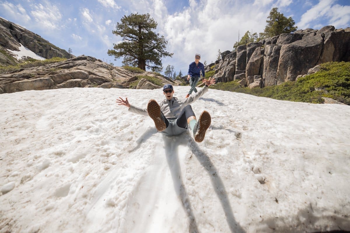 Two men slide down a snowy hill in lake tahoe in this outdoor photography shoot