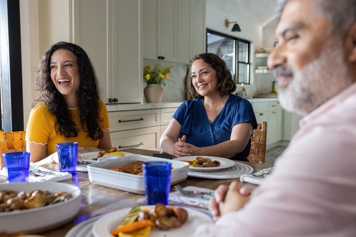 Commercial Photography of a family enjoying a meal, while a woman at the head of the table wears an Abbott CGM Sensor.