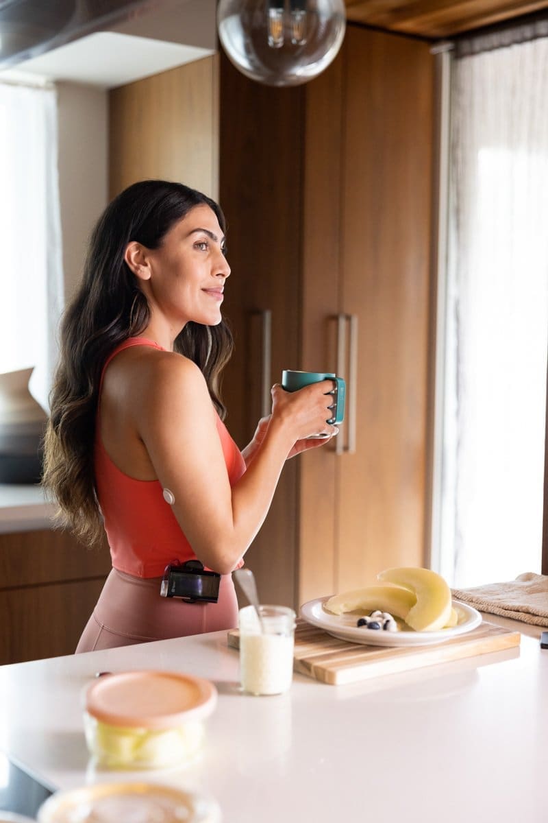 a woman wearing an Abbott CGM Sensor holds a cup of coffee in her kitchen for this commercial photography shoot