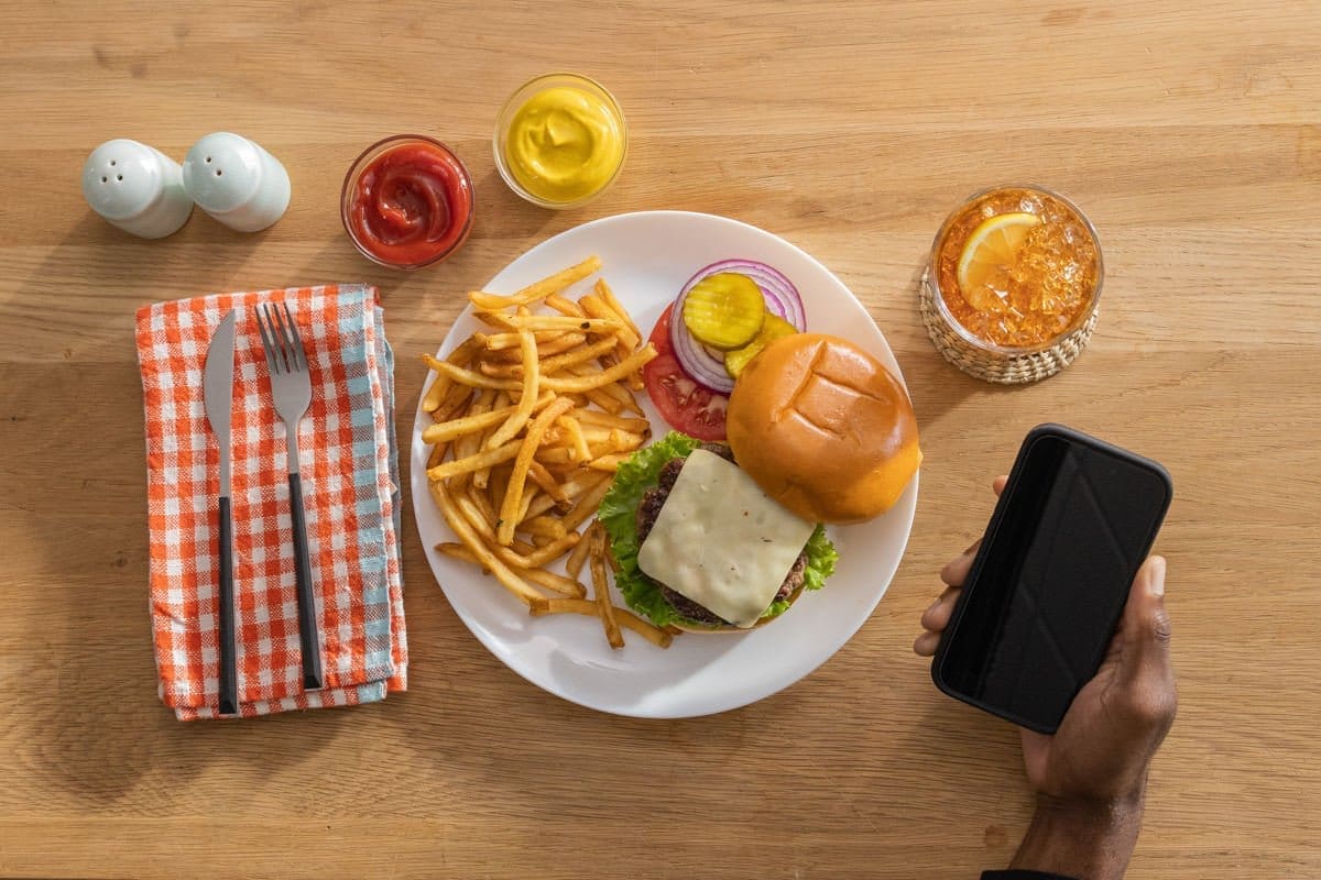 a person prepares to monitor their glucose levels before eating a burger and fries in this commercial photograph for Abbott