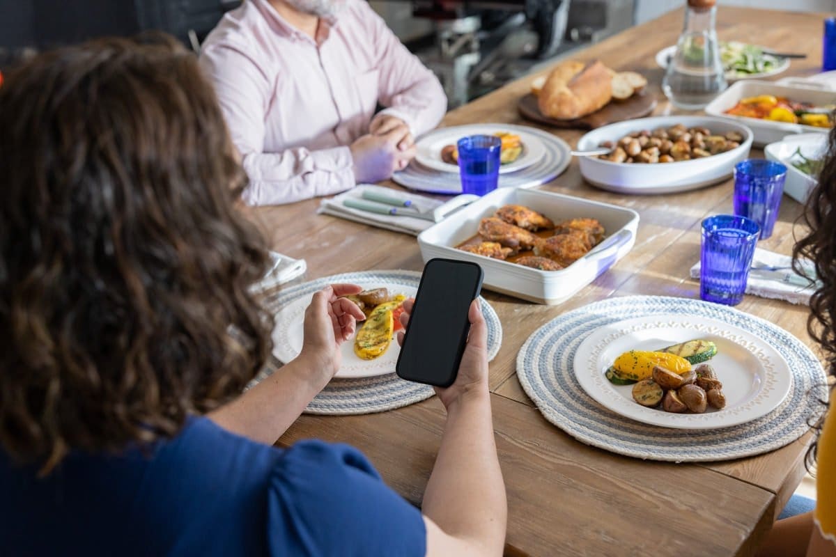 a woman monitors her glucose levels at the dinner table in this commercial photograph for Abbott