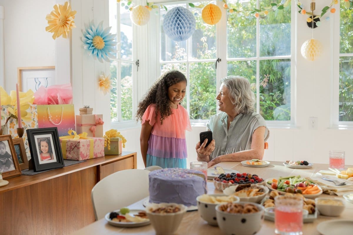 a woman wearing an Abbott CGM Sensor shows a young girl a picture on her phone in this commercial photograph