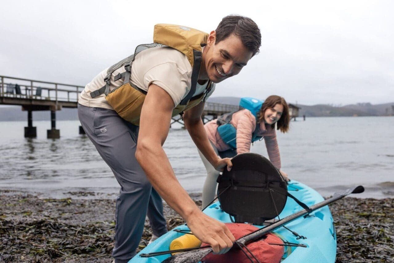 Outdoor lifestyle photography as a couple prepares to bring their kayak on shore