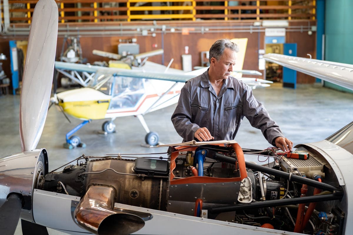 Commercial Photography for CA Community Colleges as a repairman works on a plane engine