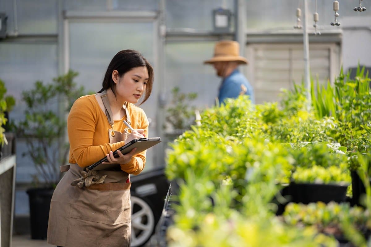 Commercial Photography of a CA Community College Student taking notes as she watches over a greenhouse