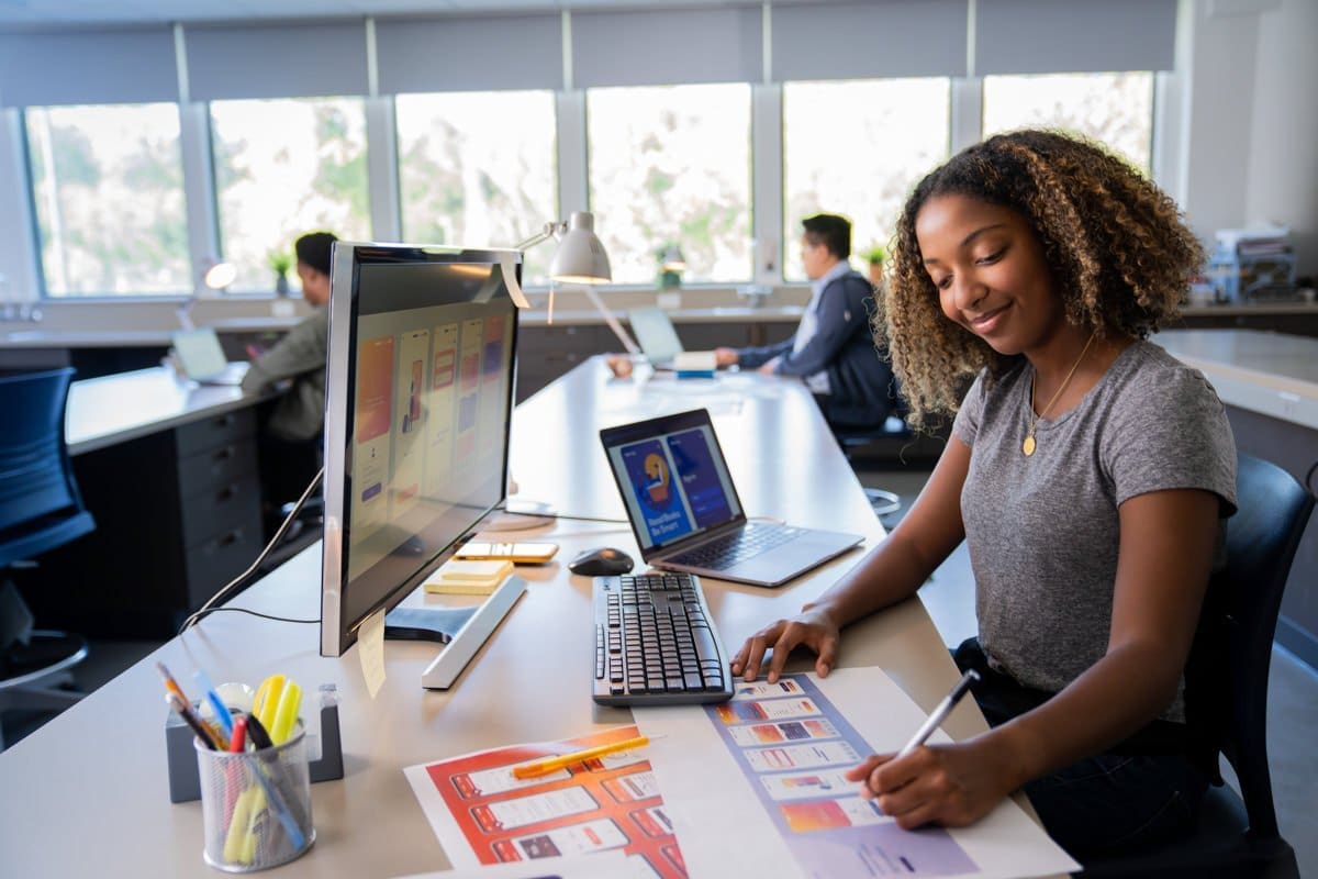 a student takes notes as she works on her computers in this commercial photograph for CA Community Colleges