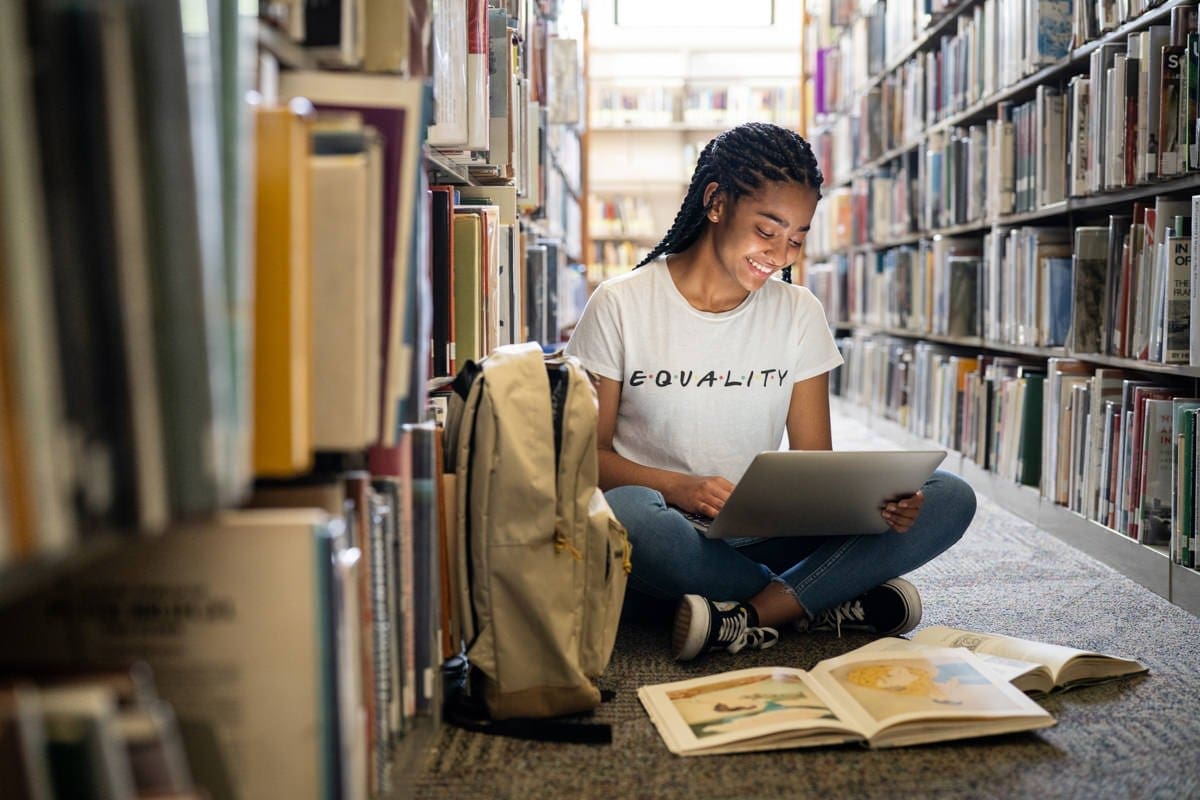 a student reads on her laptop in a library in this commercial photograph for CA Community Colleges