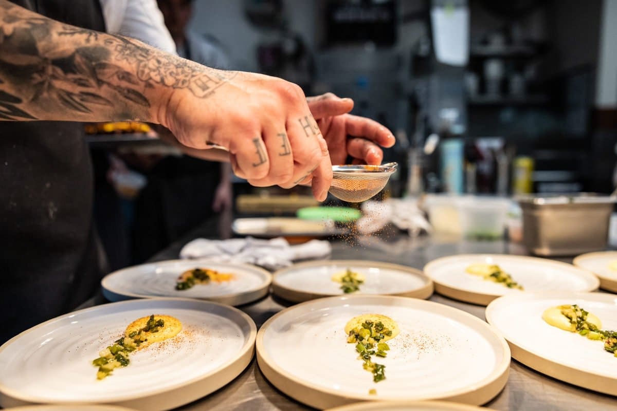 food photography as a chef lighty dusts a plate with spices