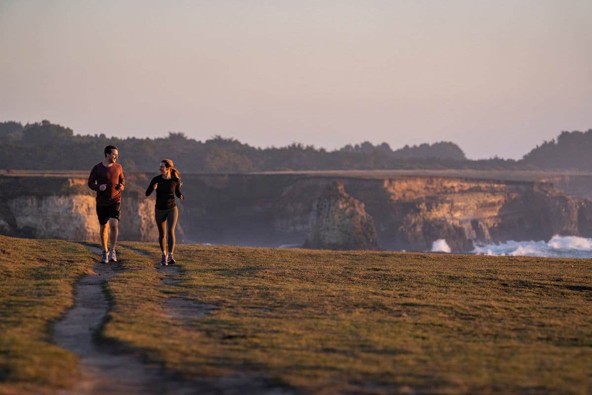 a couple jogs along the california coast in this outdoor lifestyle photography